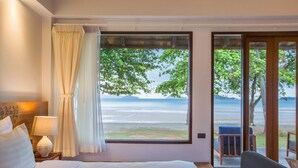 Une chambre d’hôtel dotée d’une grande fenêtre donnant sur la plage et l’océan.