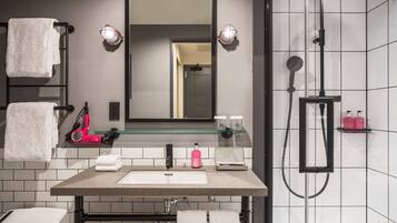 A modern bathroom with a large mirror, a sink, a towel rack, a hairdryer, and a shower area.