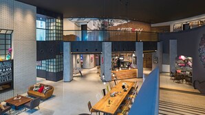 Un interior moderno con una larga mesa de madera, asientos y una zona de bar.