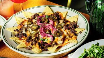 A plate of nachos topped with meat, cheese, jalapeños, and red onions.