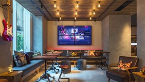 Un área de estar moderna con un televisor de pantalla plana grande, asientos cómodos y un techo de madera con vigas a la vista.