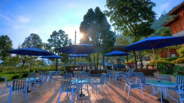 An outdoor patio area with blue umbrellas, white chairs, and tables. - AiShangXiWeng B&B (Wufeng)