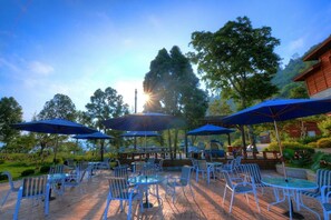 An outdoor patio area with blue umbrellas, white chairs, and tables. - AiShangXiWeng B&B (Wufeng)