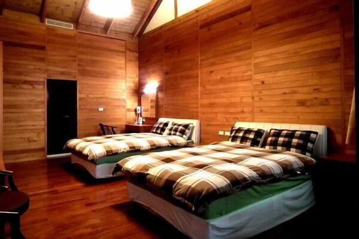 A wooden-paneled room with two beds, a desk, and a chair.