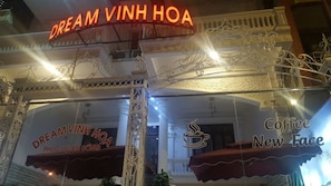 Um edifício com grades brancas ornamentadas e uma placa com a inscrição 'DREAM VINH HOA PHU CUA ANUONG'.