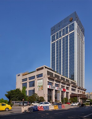A tall modern building with a glass facade and a logo on the top. - Yinxin Century Hotel (Chongqing)
