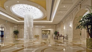 Un hall d’entrée spacieux, agrémenté d’un grand lustre, d’un sol en marbre et d’un comptoir d’accueil.