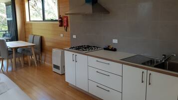 A modern kitchen with a gas stove, white cabinets, and a large window overlooking greenery.