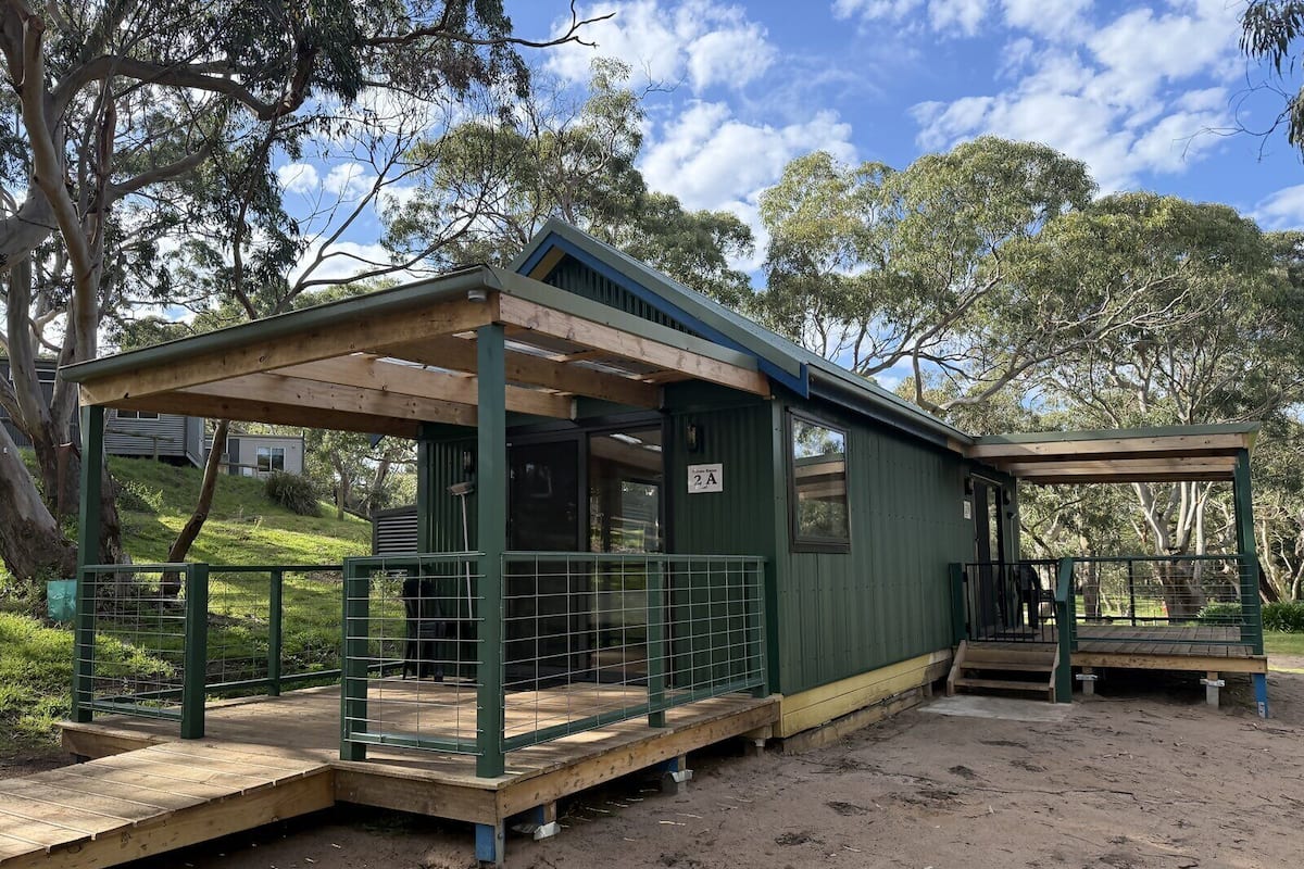 A small, single-story building with a covered porch and a fenced outdoor area.