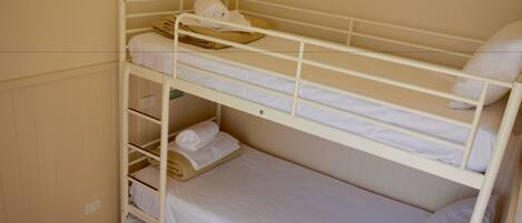 A bunk bed with white bedding and a towel on the top bunk.