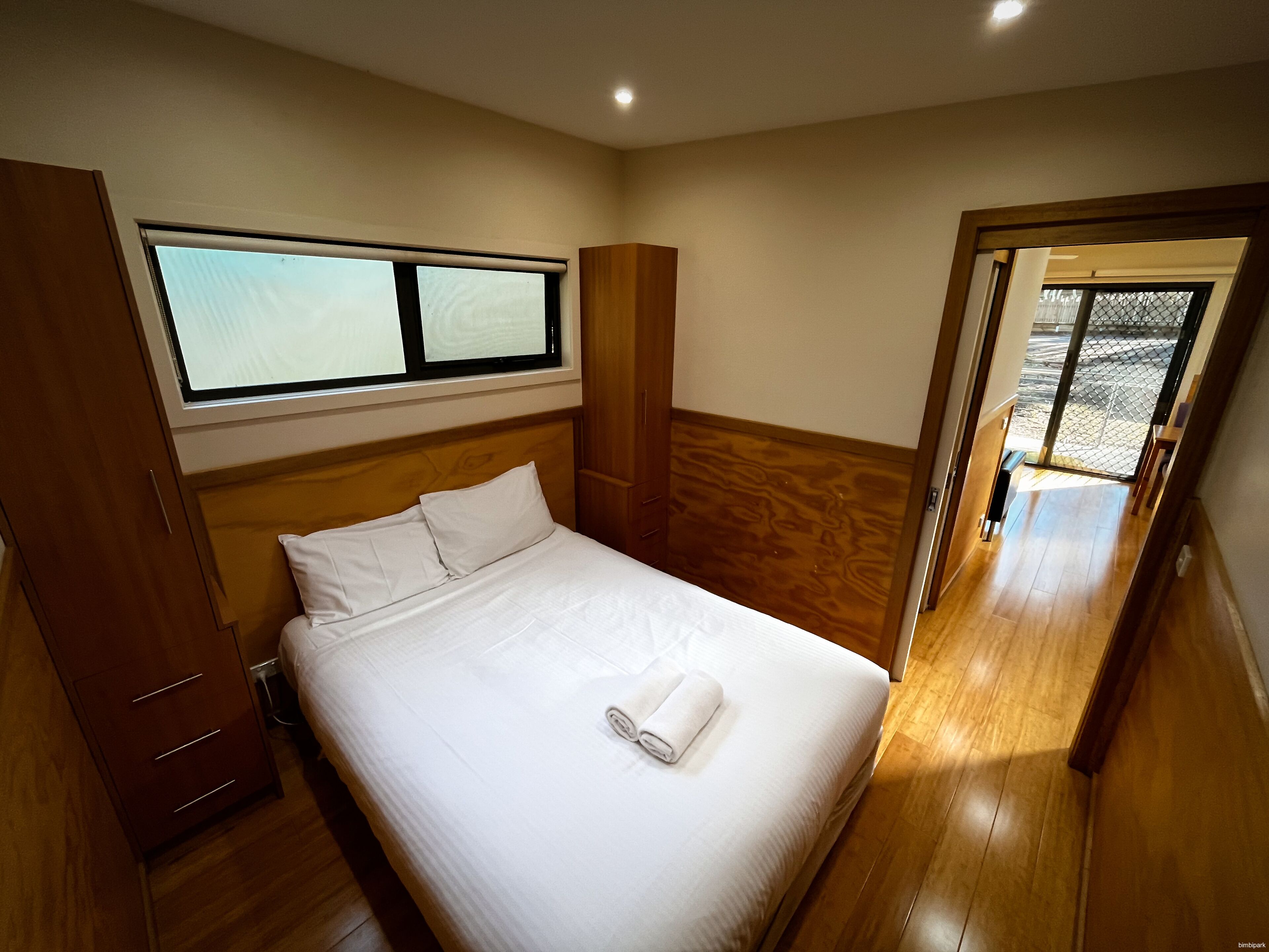 Een slaapkamer met een bed, een houten garderobe en een raam.