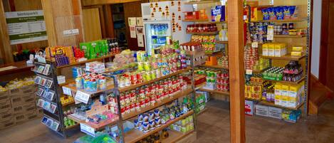 Un supermercado con estantes llenos de diversos productos alimenticios y una sección refrigerada.