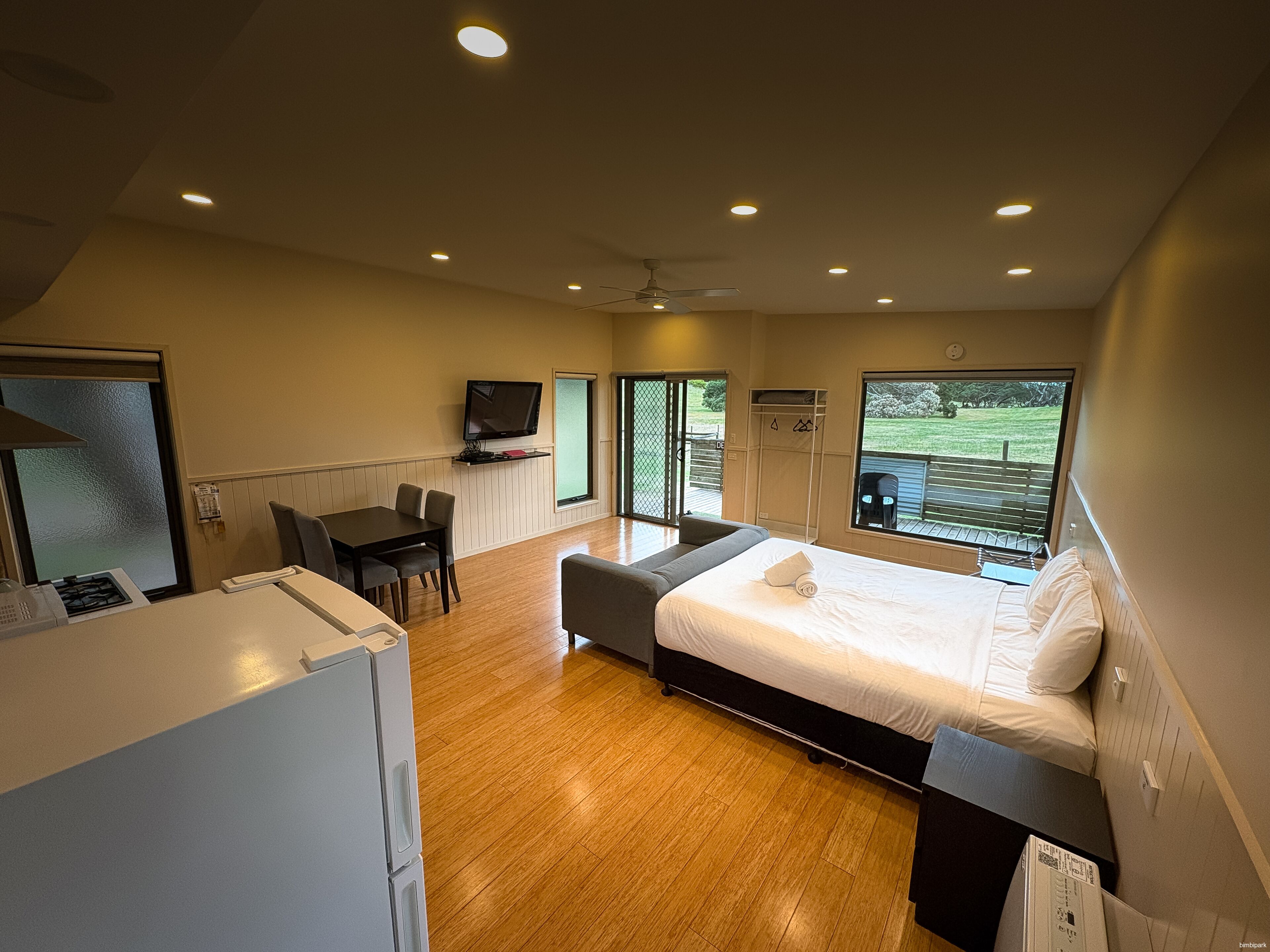 A modern bedroom with a bed, a desk, and a television.