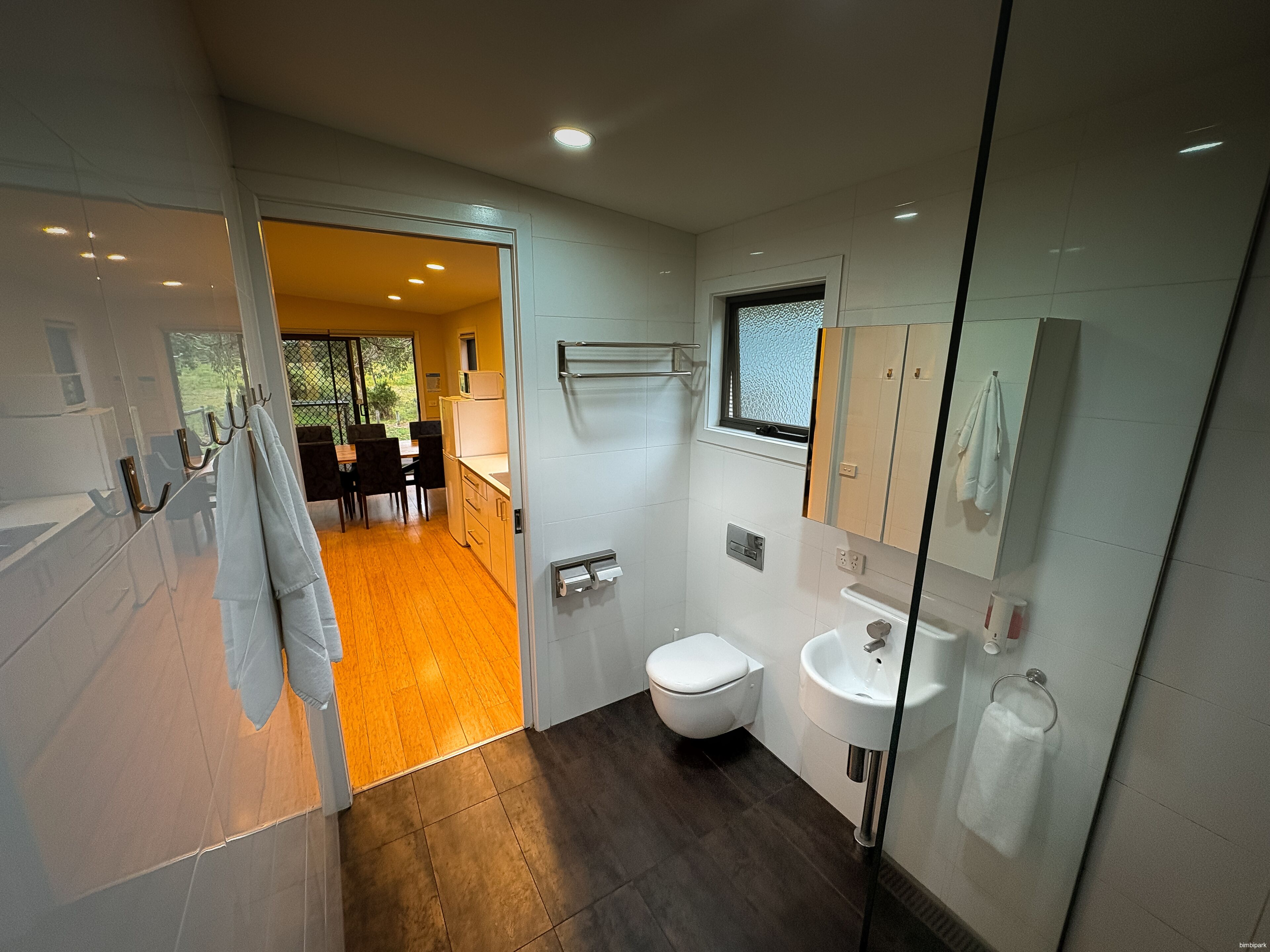 Ein modernes Badezimmer mit Toilette, Waschbecken und einer Duschkabine aus Glas.