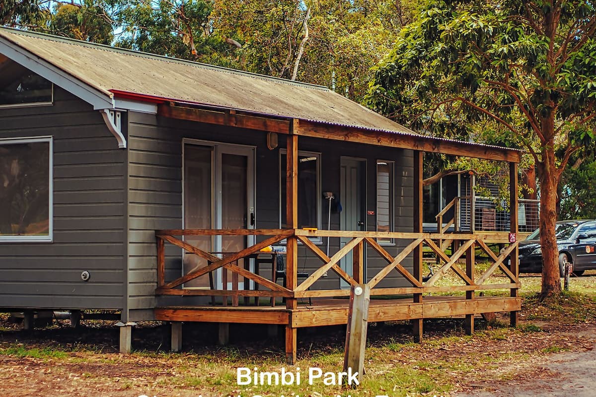 A standard cabin at Bimbi Park with a wooden deck and a metal roof.