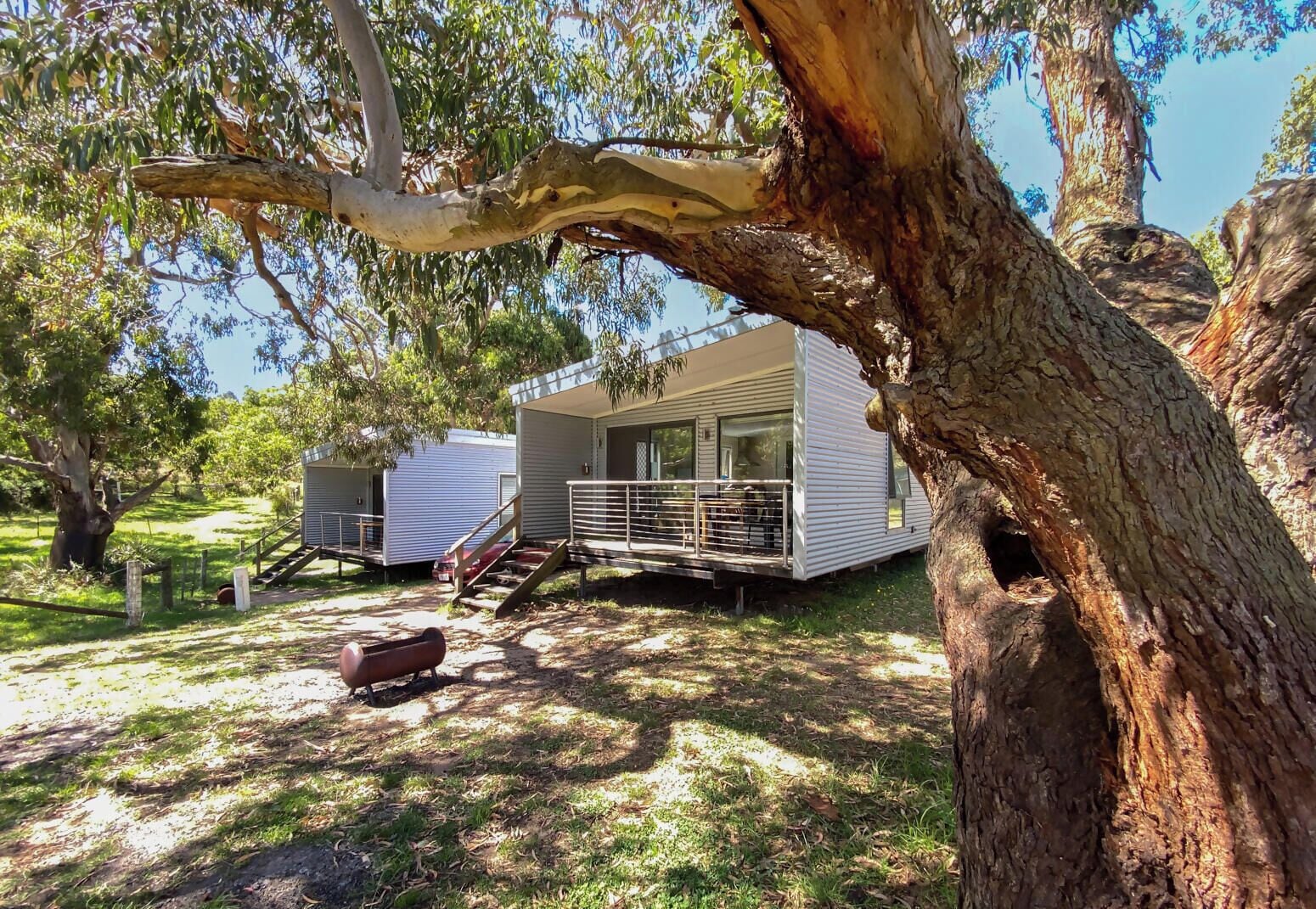 A mobile home with a porch and a staircase leading to a deck.