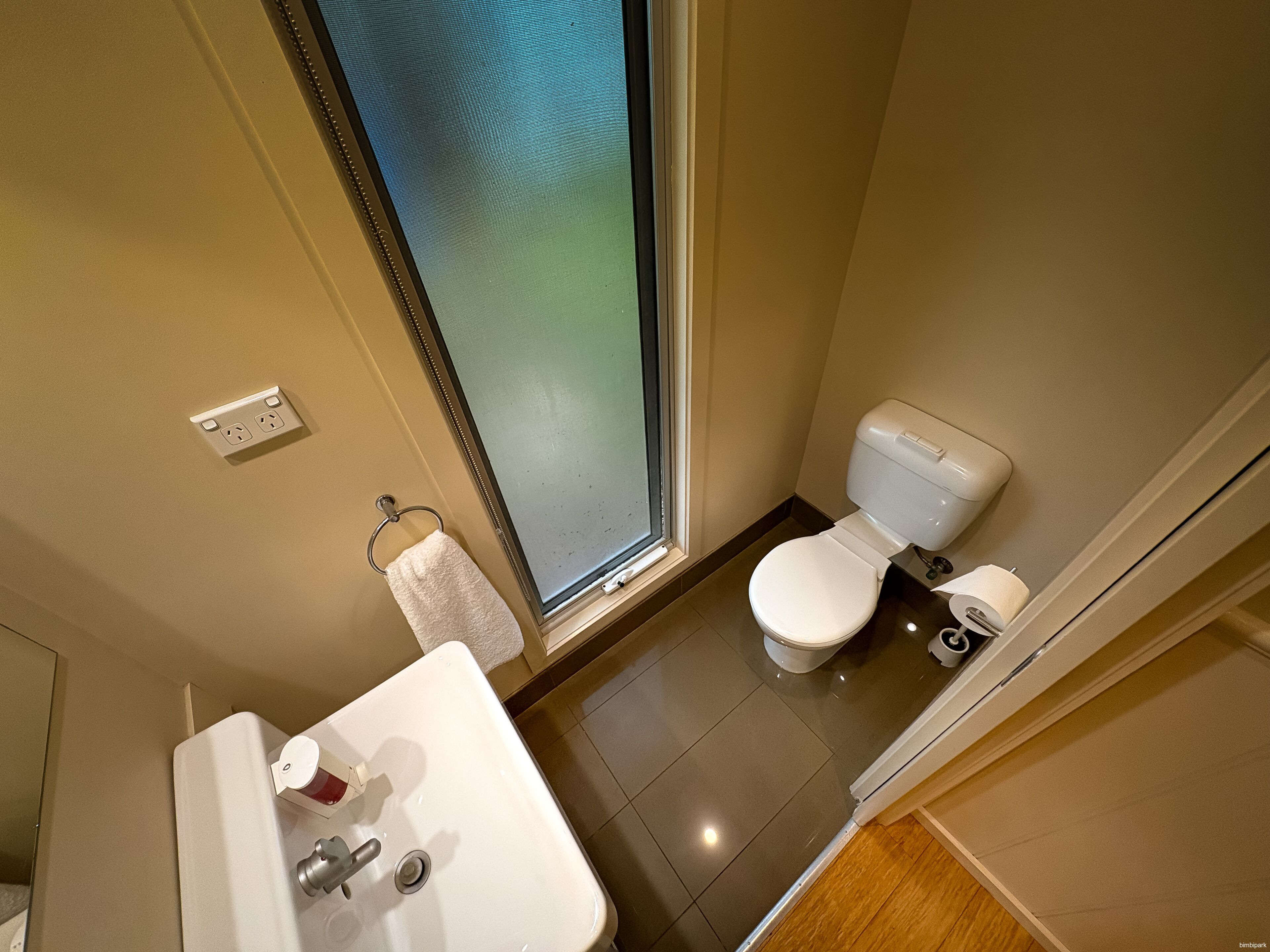 Un baño con inodoro, lavamanos y ventana.