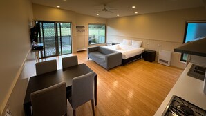 Una habitación de hotel moderna con una cama, un comedor y una cocina.