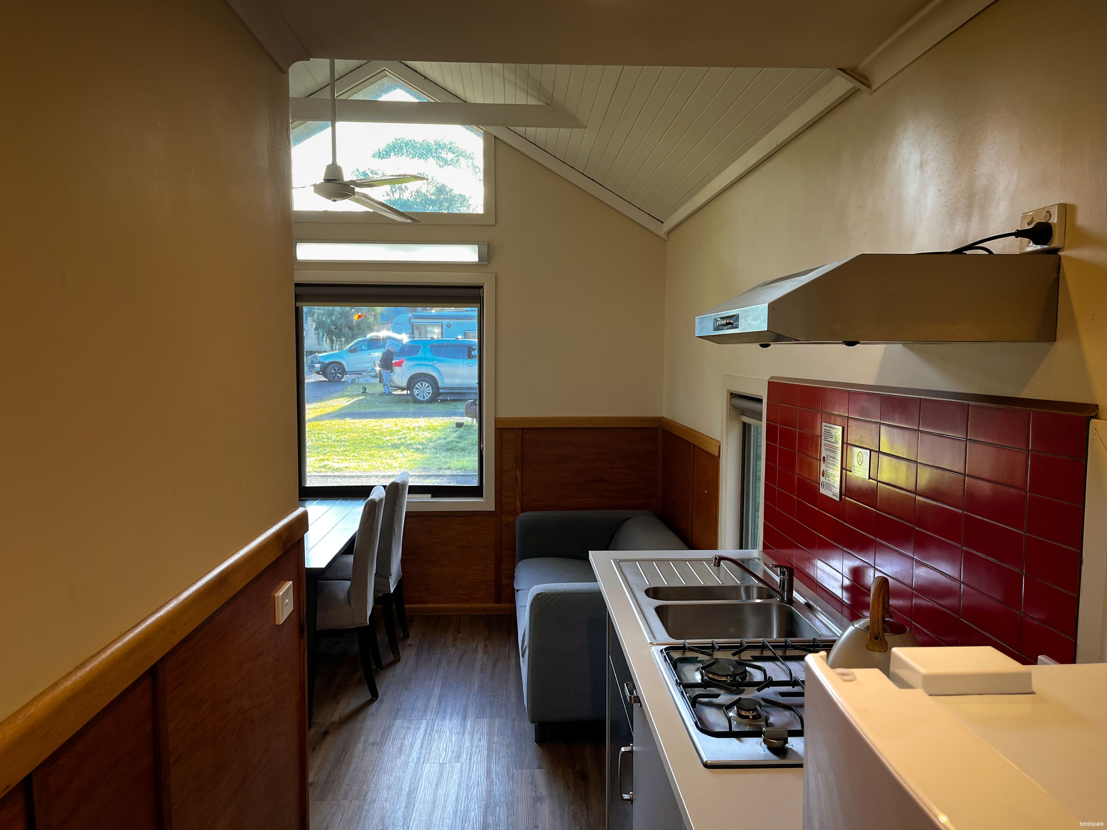 Cocina compacta con estufa a gas, pileta y ventana con vista a la calle.