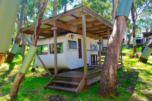 A mobile home with a covered porch, surrounded by trees.
