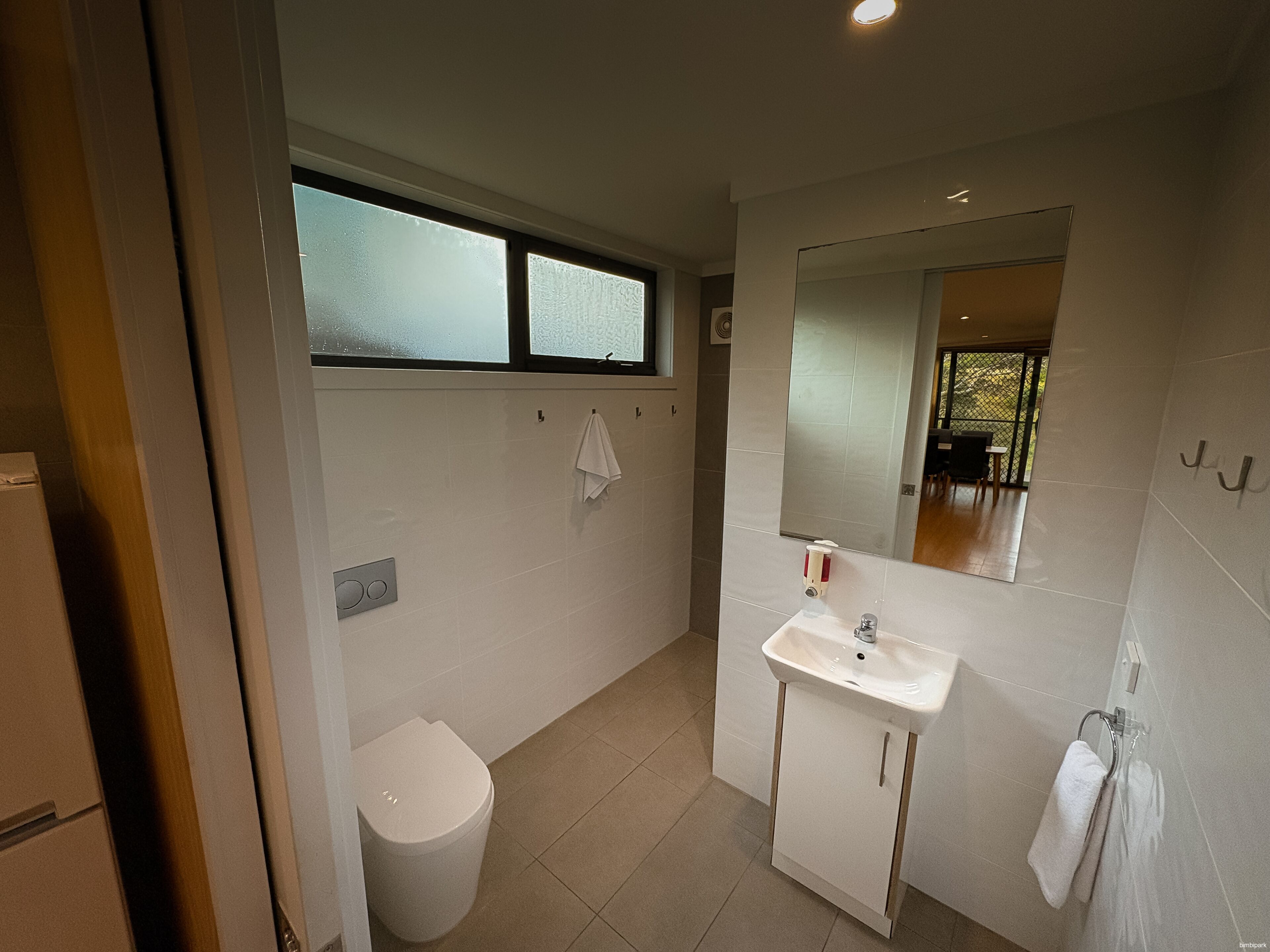 Un baño moderno con inodoro, lavamanos y espejo.
