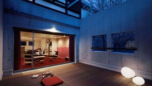 A modern outdoor living area with a wooden deck, a glass door leading to a room with a red carpet, and a night sky view. - Hoshino Resorts RISONARE Yatsugatake (Hokuto)