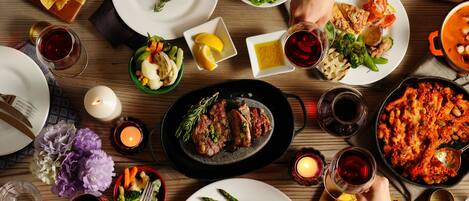 A dining table with various dishes, including steak, vegetables, and a pot of stew.