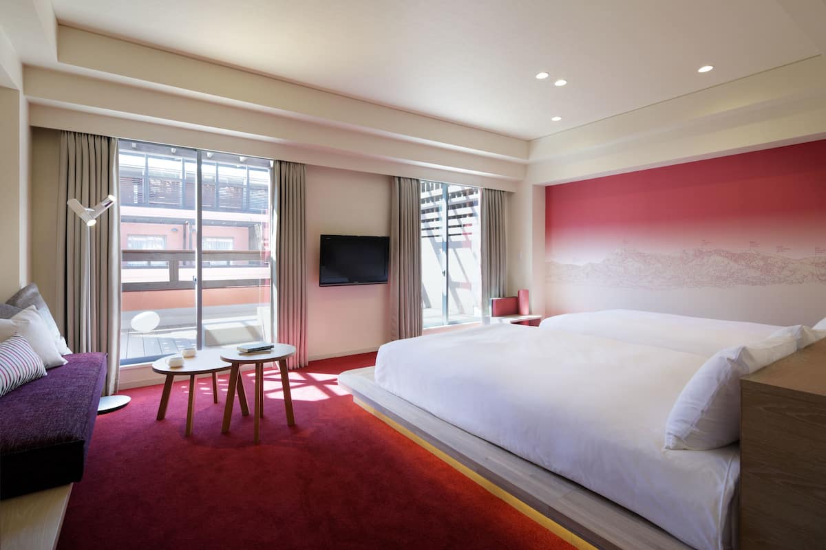 Una habitación de hotel con una cama grande, un sofá, una mesita y un televisor.