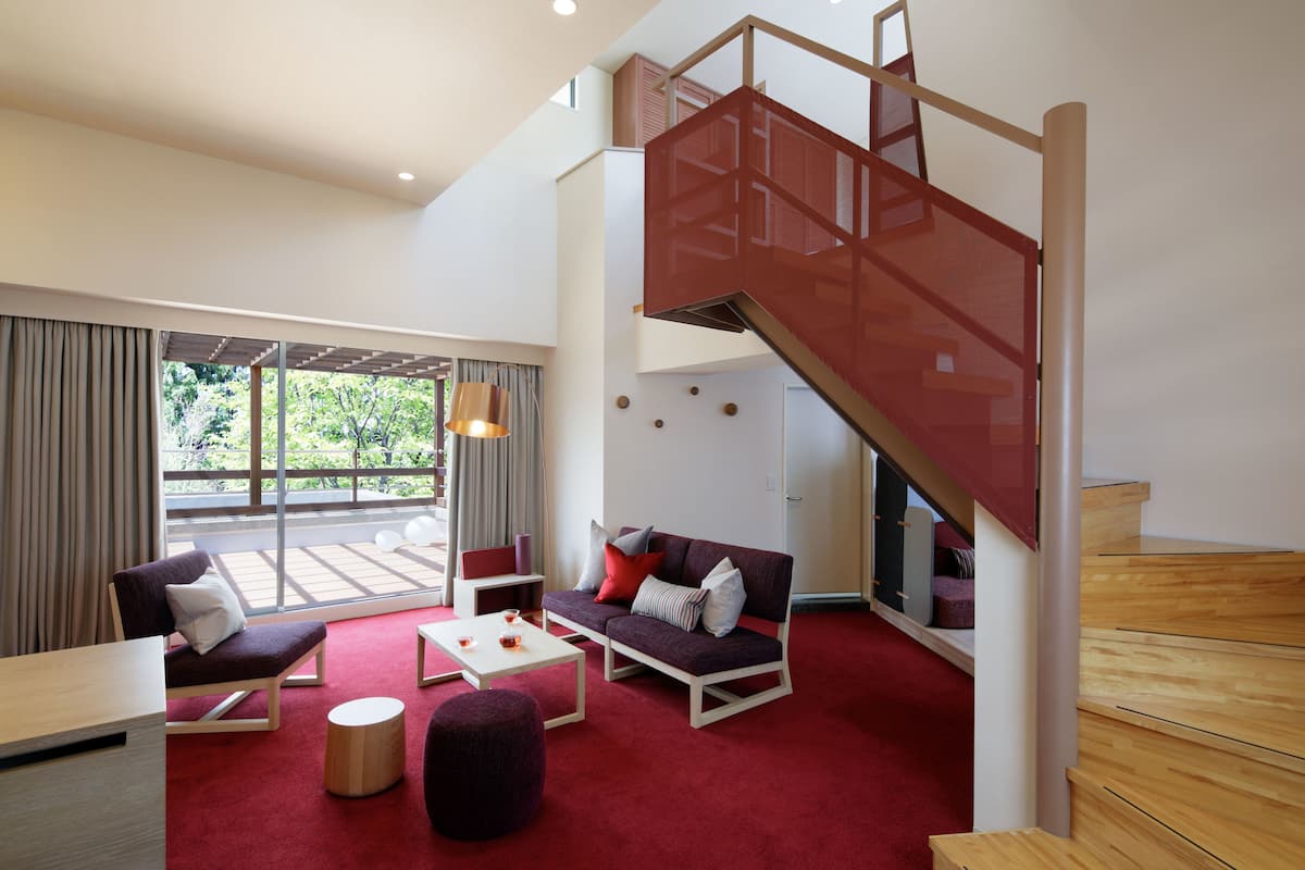Una sala de estar moderna con una alfombra roja, un sofá, una mesa de centro y una escalera.