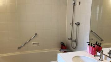 A modern bathroom with a bathtub, a shower, a vanity with a sink, and a mirror.