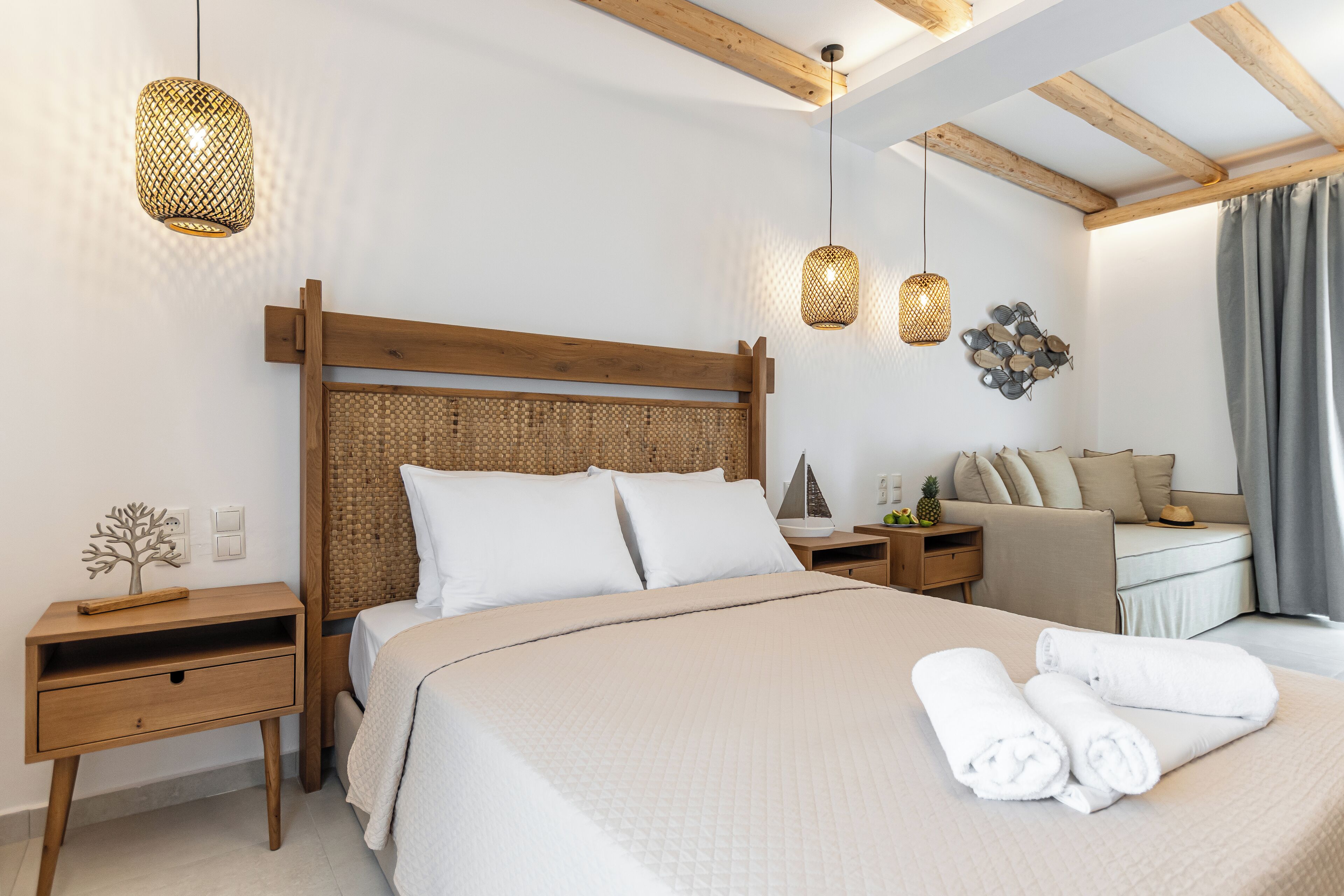 A bedroom with a wooden headboard, a bed with white linens, two bedside tables, and two hanging lights.