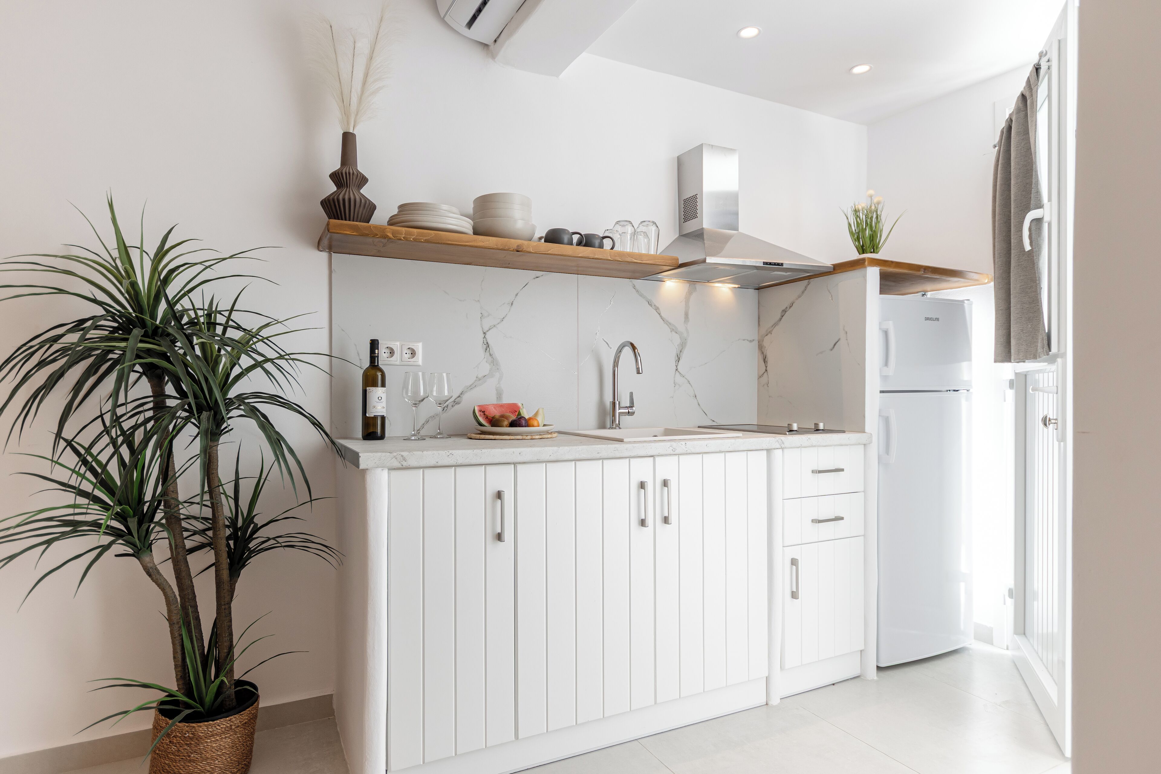 Una cocina moderna con armarios blancos, un salpicadero de mármol y un horno empotrado.