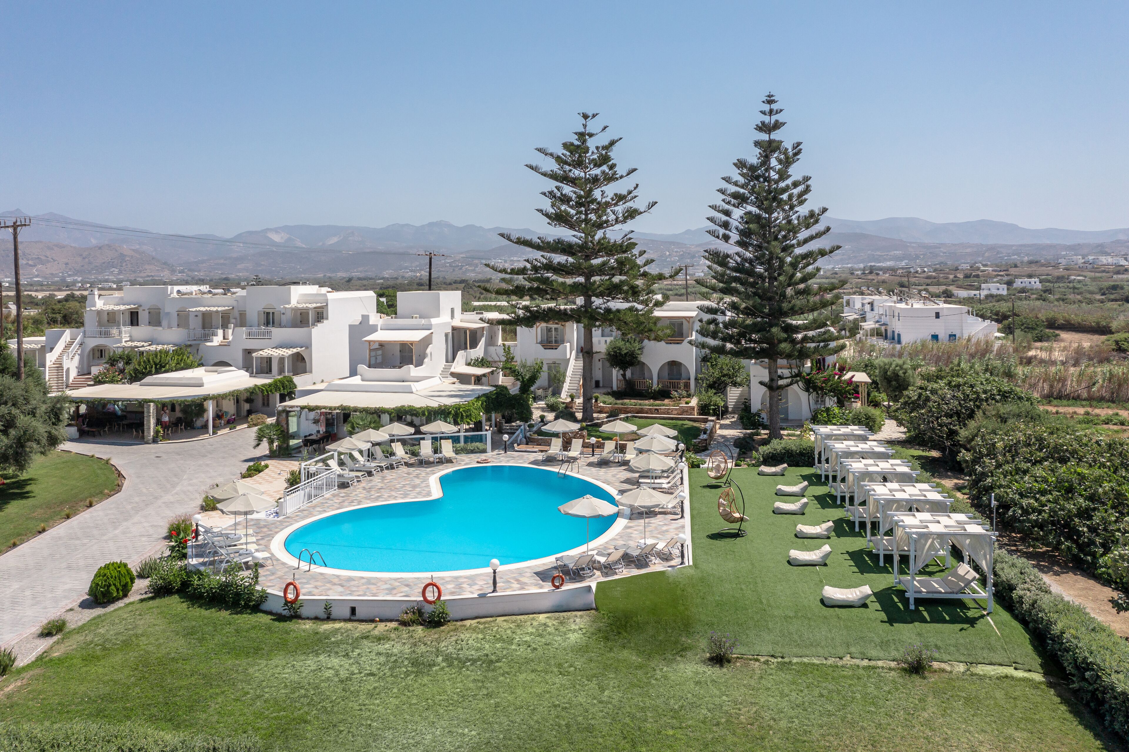 A resort with a central swimming pool, multiple buildings, and a mountainous backdrop.