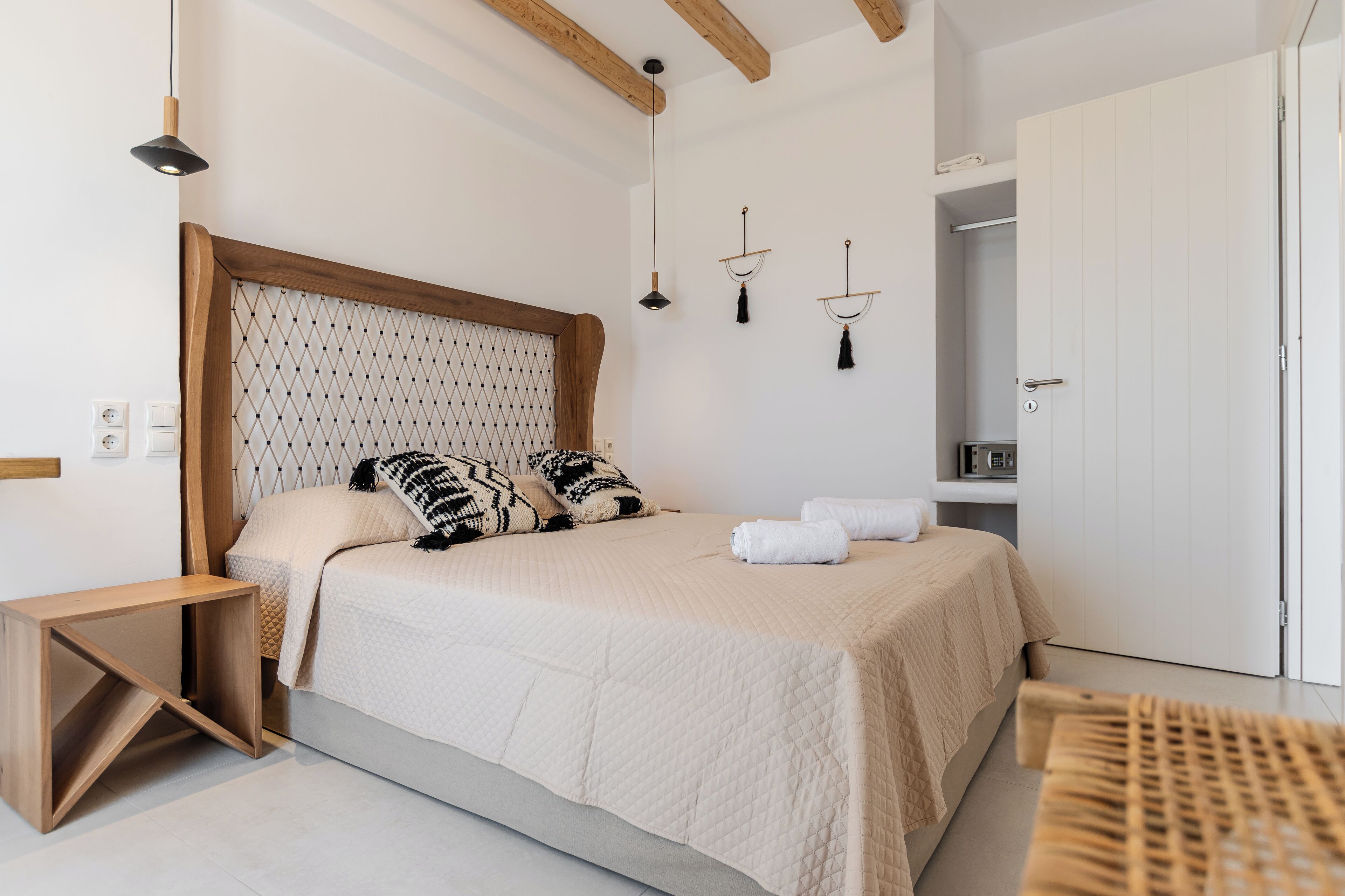 A modern bedroom with a large bed, wooden headboard, bedside tables, and a wardrobe.