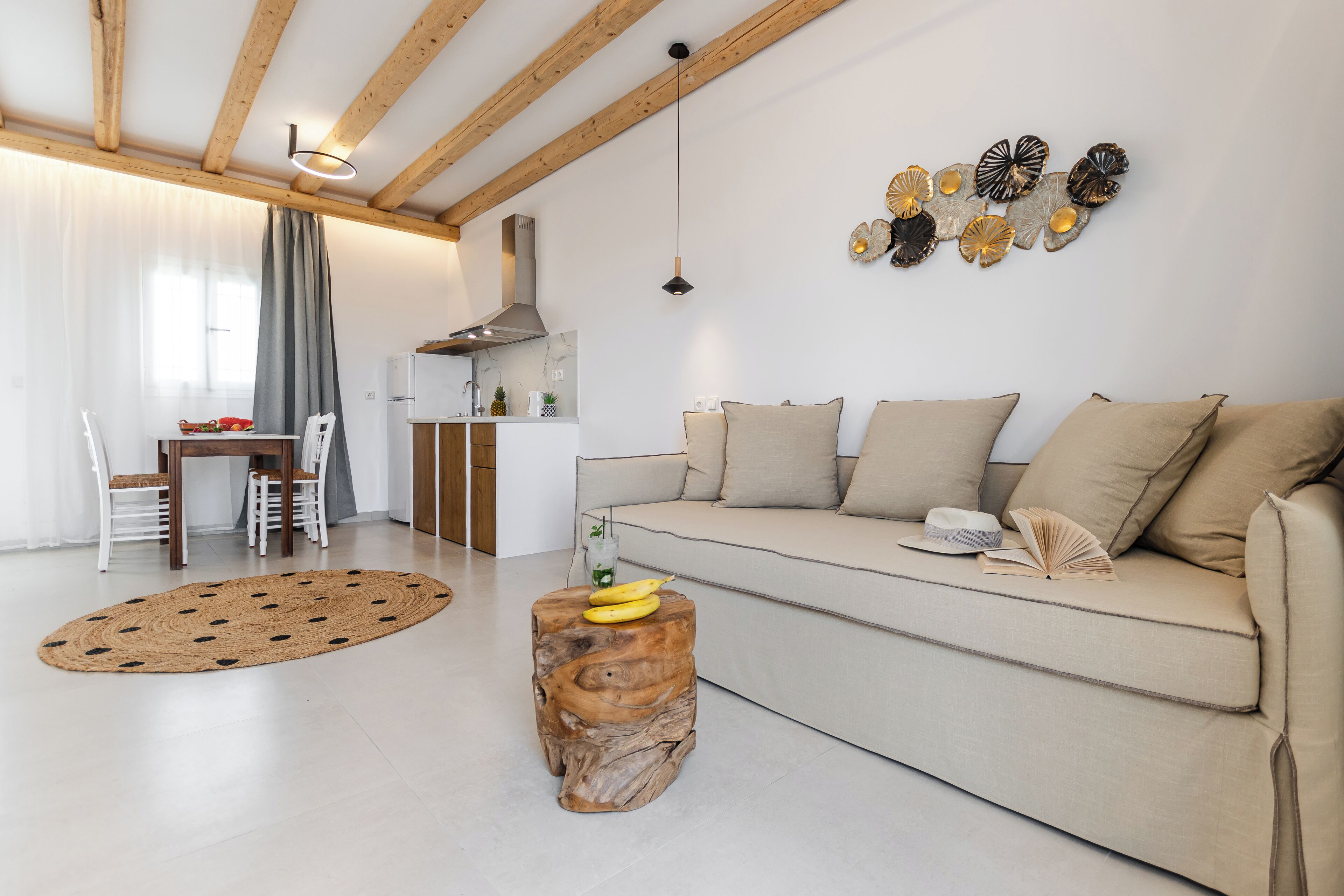 Un salon moderne avec un canapé, une table à manger et des chaises. On aperçoit un coin cuisine au fond.