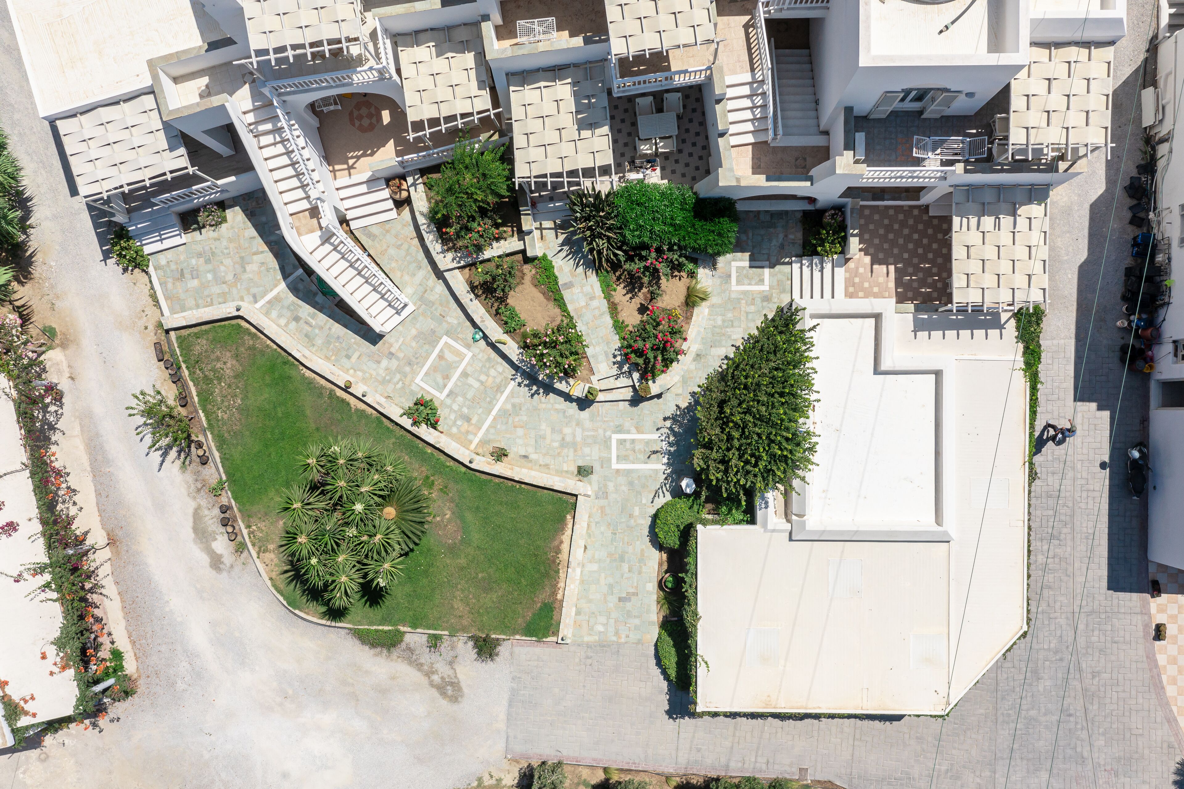 Vue aérienne d’un complexe résidentiel comprenant plusieurs bâtiments, une cour centrale agrémentée de verdure et un espace de stationnement.