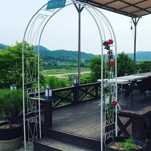 Un patio exterior con un arco de metal, una mesa y sillas.