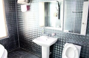 Un baño con lavamanos blanco, inodoro y zona de ducha.