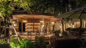 An outdoor seating area with wicker furniture and a bar with illuminated shelves. - Marriott Executive Apartments, Bangkok Townhall Sukhumvit (Bangkok)