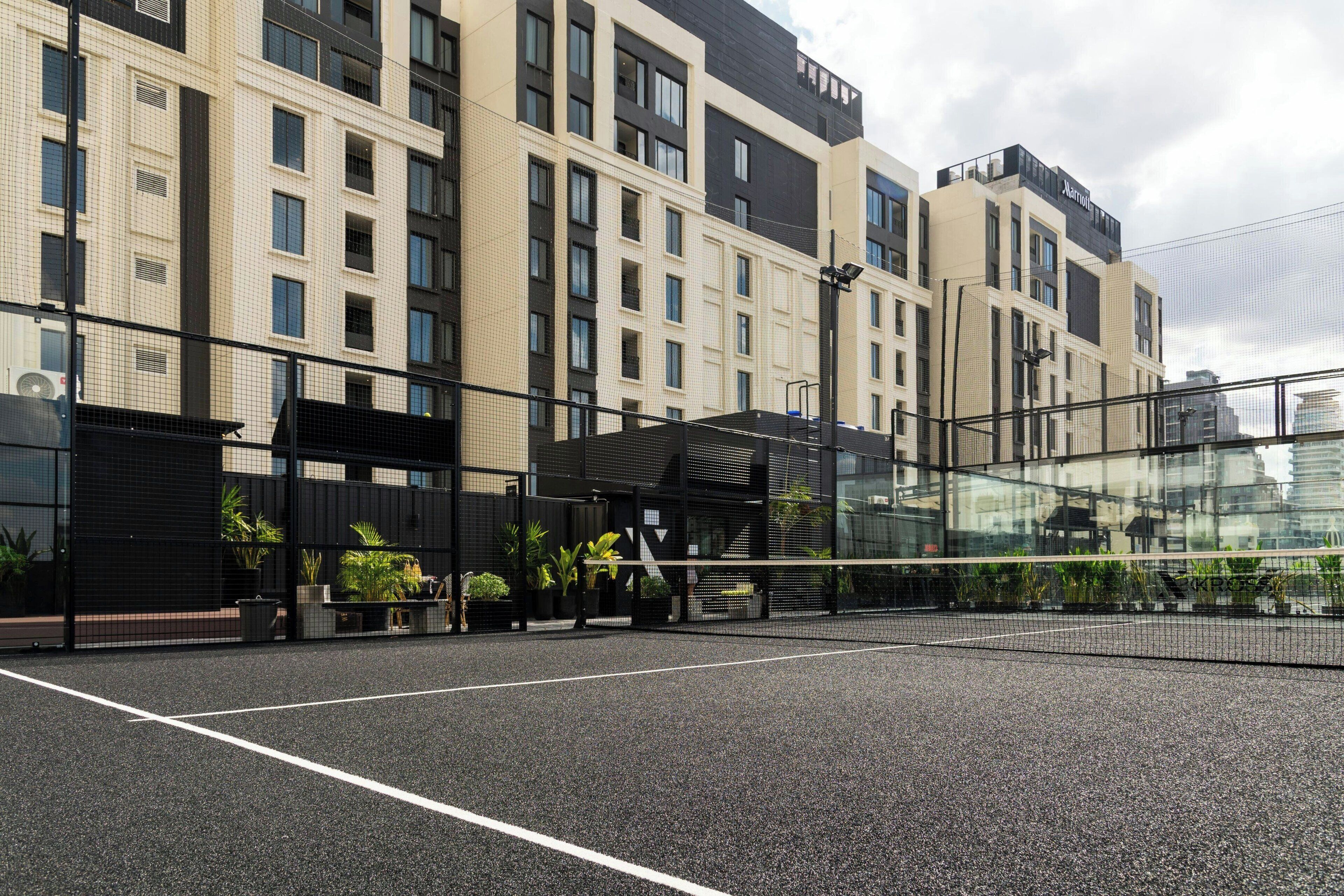 A modern building with a tennis court in front.