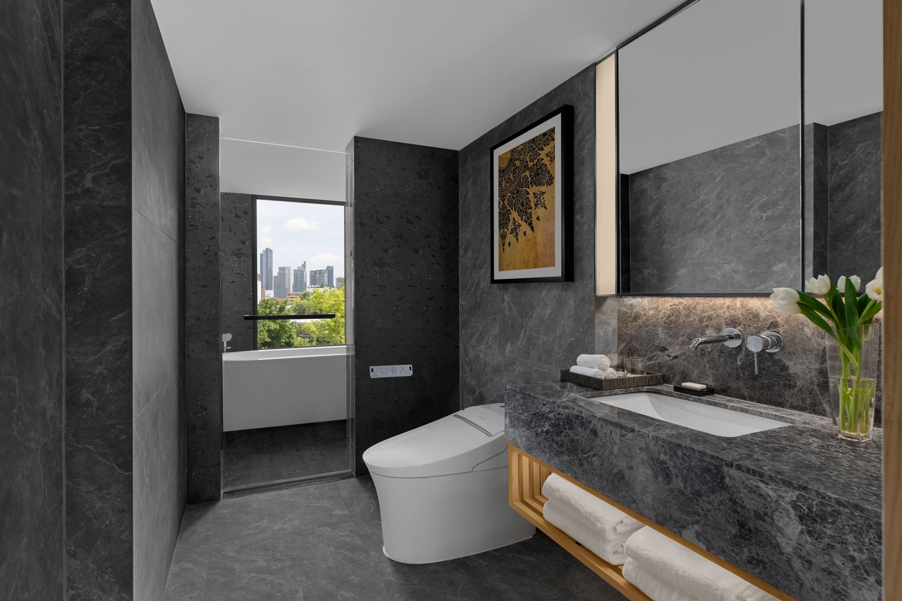 A modern bathroom with a toilet, sink, and large mirror.
