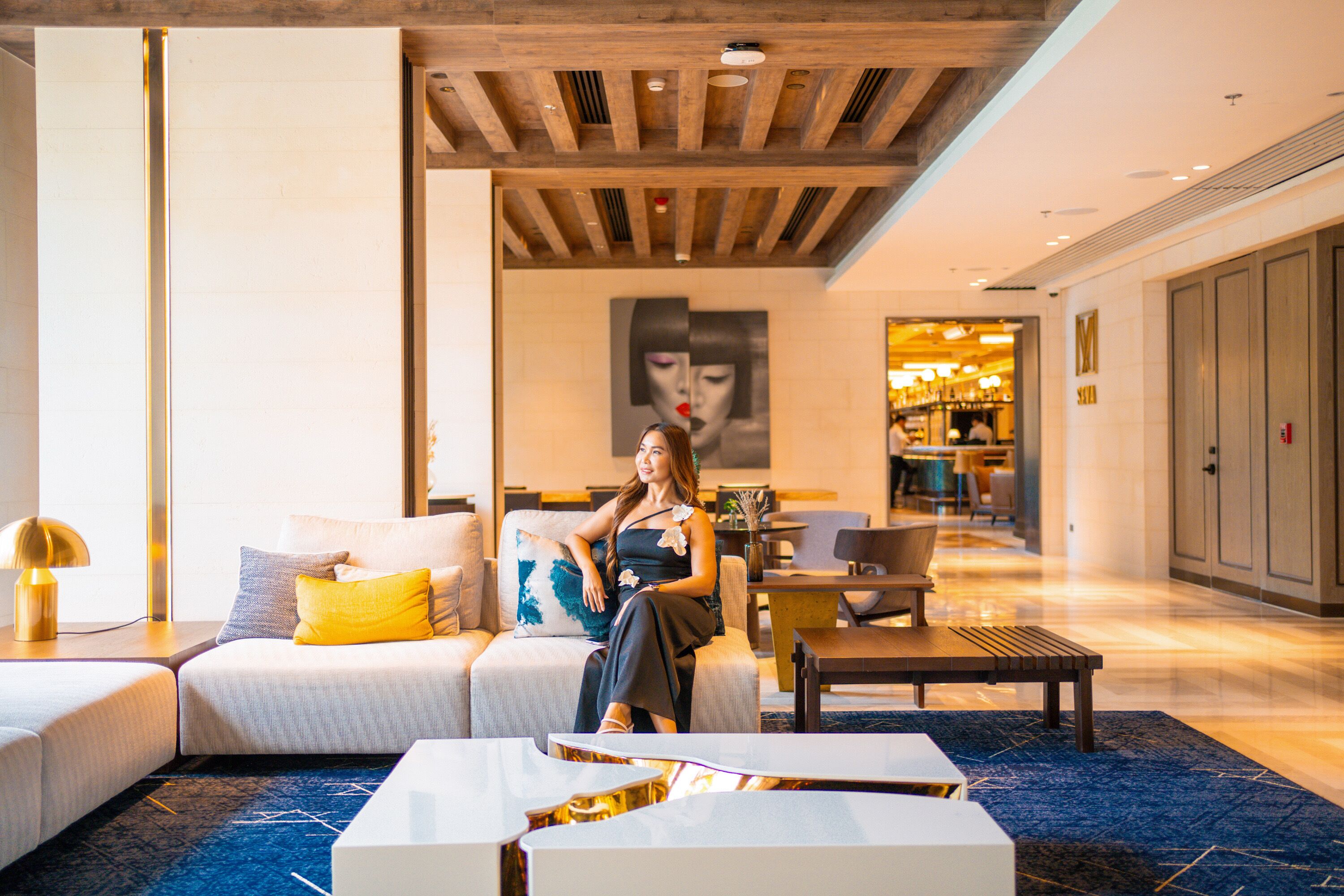 Un vestíbulo de hotel moderno con un sofá, una mesa de centro y una zona de comedor.