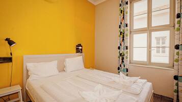 Habitación de hotel con cama, mesita de noche, lámpara y ventana con cortinas.