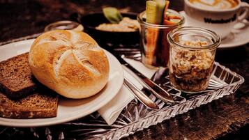 A table with a loaf of bread, a glass of iced coffee, and a jar of granola.