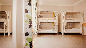 Una habitación con literas, una cortina estampada y piso de baldosas.