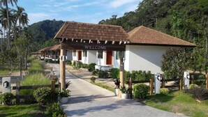 A row of single-story buildings with a 'WELCOME' sign, surrounded by greenery and hills.