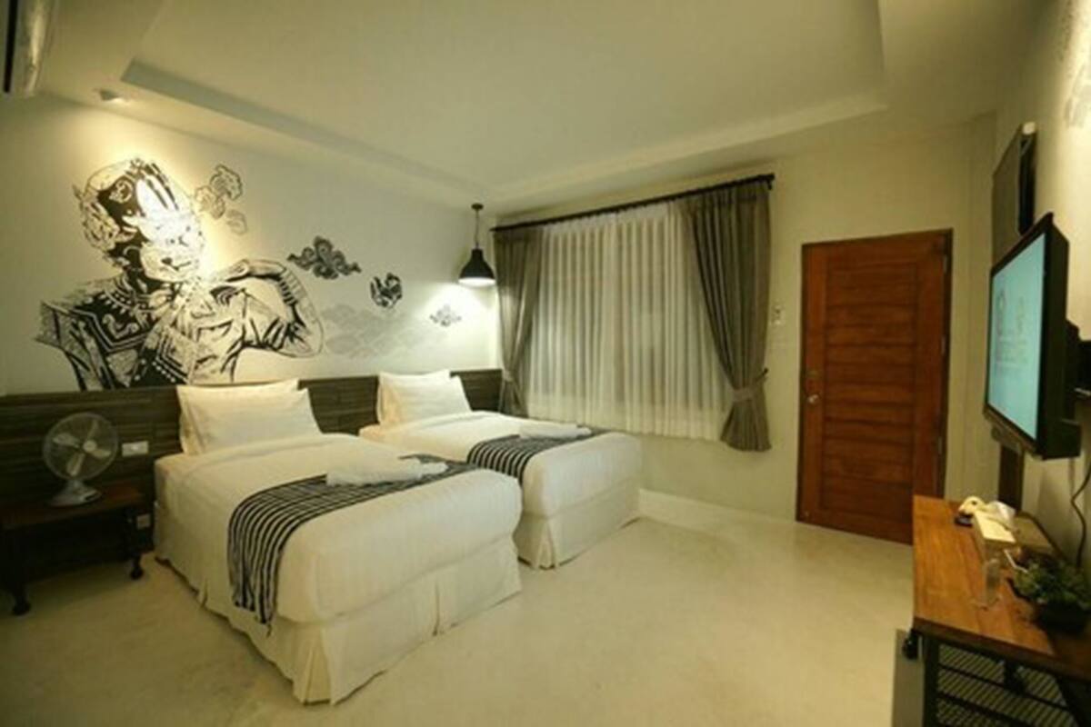Een hotelkamer met twee bedden, een muurschildering, een televisie en een houten deur.