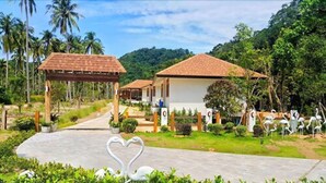A resort with multiple bungalow-style buildings, a central pathway, and a heart-shaped sculpture in the foreground.