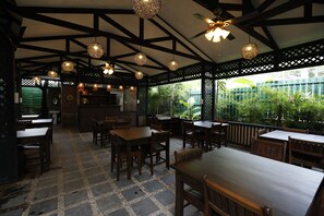 A restaurant with wooden tables and chairs, a tiled floor, and hanging spherical light fixtures. - Cloud 10 Boutique Hotel (Yangon)