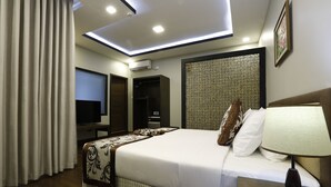 Quarto de hotel moderno com uma cama grande, televisão de tela plana, escrivaninha e luminária no teto.